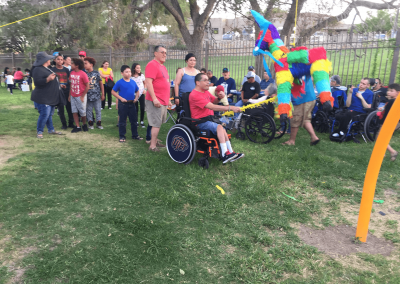 young adult with wheelchair hitting pinata